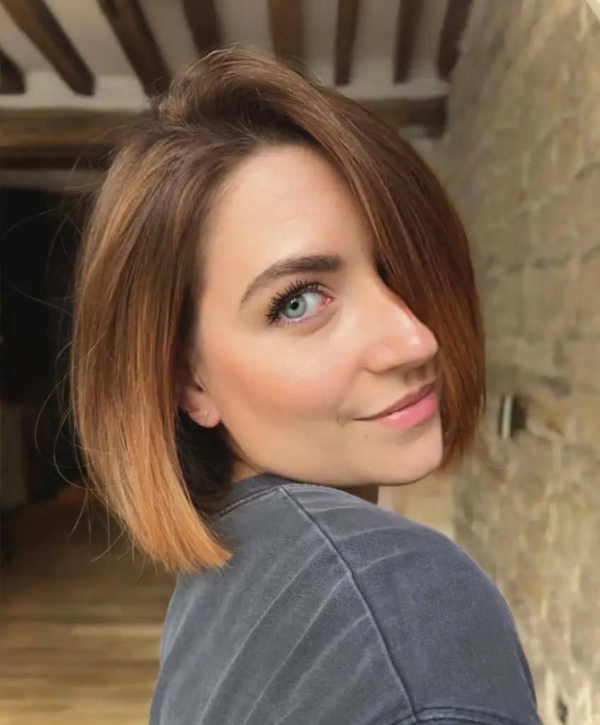 Raven karamelno rjav bob z nežnim balayage prelivom in toplimi svetlimi odtenki za moderen videz.