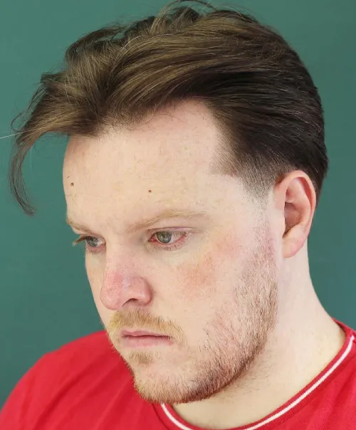 Urejena moška frizura s sredinskim razdelkom, primerna za okrogel obraz.