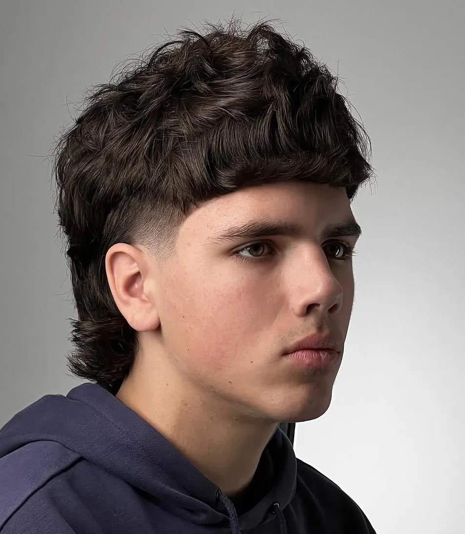 Razmršena mullet frizura z naravnimi kodri za ovalen obraz.