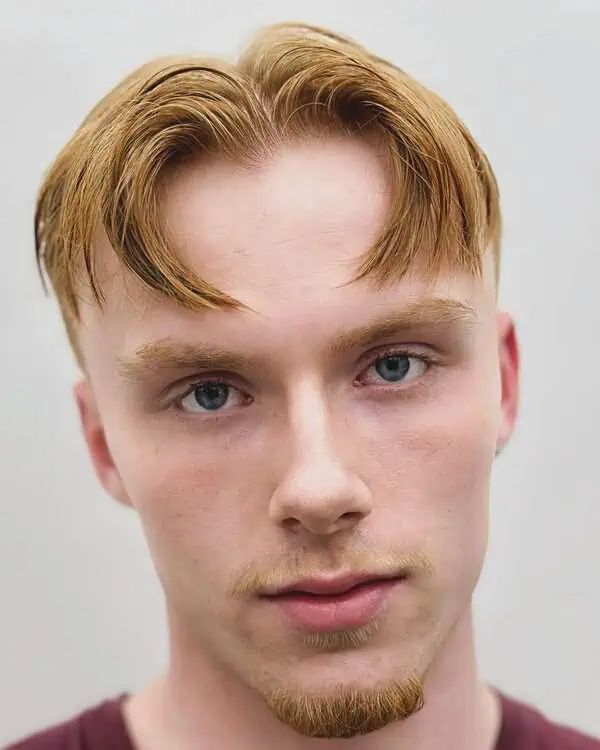 Moška frizura s sredinskim razdelkom in rahlo ukrivljenimi prameni, primerna za srčasto obliko obraza.