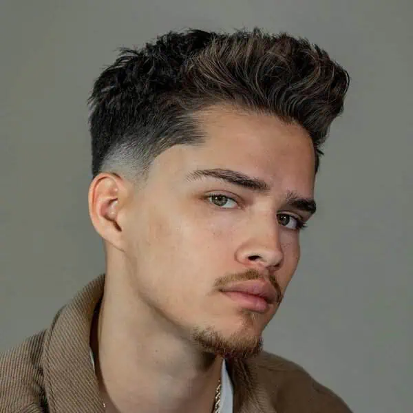 Moška frizura s temple fade prehodom in daljšim vrhom, primerna za srčasto obliko obraza.