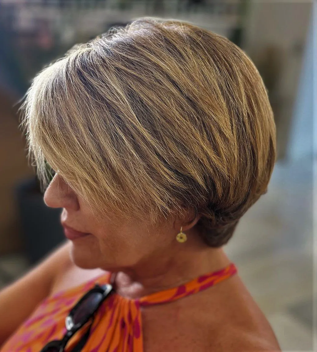 Kratka teksturirana paž pričeska s svetlimi prameni, ki dodajo dimenzijo in pomladijo videz.