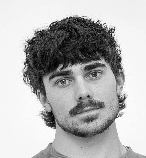 Moderne frizure za moške 23 Srednje dolga moška mullet frizura z gostim frufrujem in razmršenim videzom.